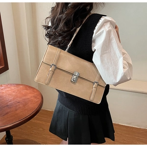 Side view of khaki faux leather shoulder bag with silver buckles on a wooden table