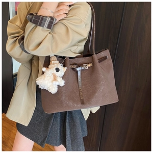 Détail d'un sac cabas en cuir marron texturé avec un joli pendentif ours en peluche