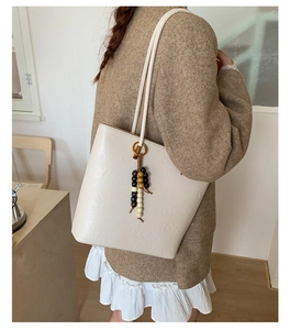 Detail of minimalist tote bag featuring vintage wooden bead tassel and fashion embossing