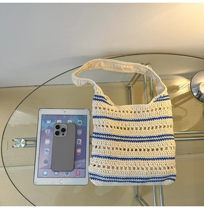 Top view of woven crochet shoulder bag with blue stripes and hollow texture on a table