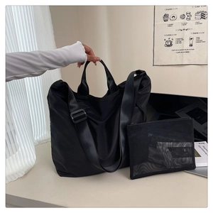 Close-up of waterproof black nylon tote bag with matching mesh zipper pouch and strap