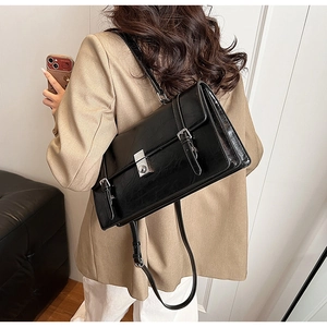 Close-up of minimalist black vintage underarm bag featuring a metallic swivel lock