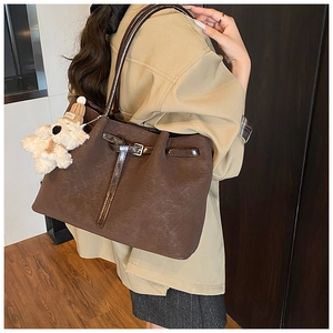 Gros plan du sac cabas marron texturé avec boucles brillantes et breloque peluche chien