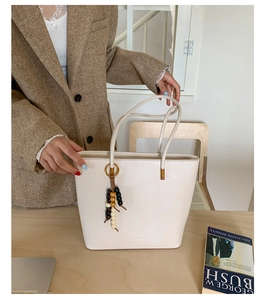 Detail view of off-white tote bag with vintage wooden beads on minimalist leather handle