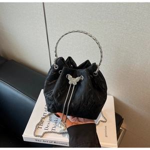 Détail du sac seau noir plissé avec poignée ronde argentée et breloque papillon en perles