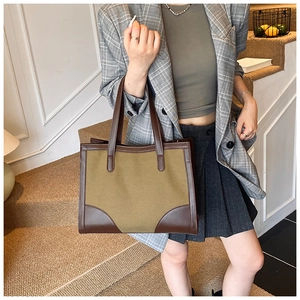 Détail d'un grand sac cabas en toile avec garniture en cuir marron porté en bandoulière