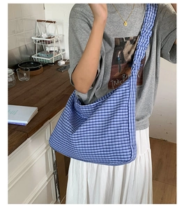 Detail view of blue and white checkered hobo bag with ruffled pleated shoulder strap