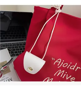 Detail of red canvas tote bag with embroidery and a white leather mini pendant charm