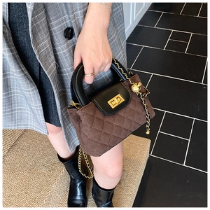 Close-up of diamond quilted crossbody bag with gold lock and metal chain strap detail