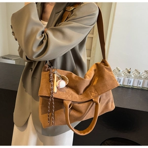 Détail d'un grand sac cabas en daim marron avec porte-clés de baseball et bandoulière