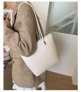 Detail showing the textured cream white leather tote bag with slim shoulder strap