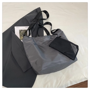 Overhead view of gray nylon tote bag with black straps and mesh pouch on white linen