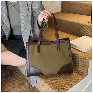Détail d'un grand cabas en toile olive avec finitions en cuir marron sur escalier