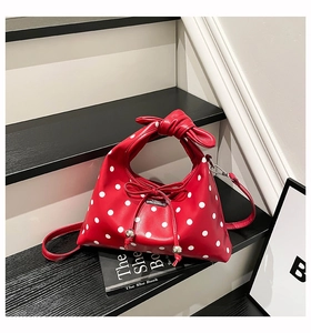 Detailed macro view of the red polka dot bag with knot handle and bow accent