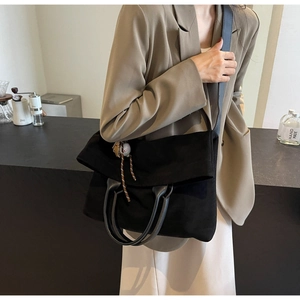 Détail d'un grand sac fourre-tout noir avec anses en cuir et pendentif de baseball