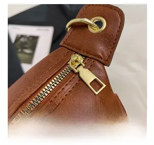 Close-up of golden zipper and textured brown leather on vintage crossbody dumpling bag
