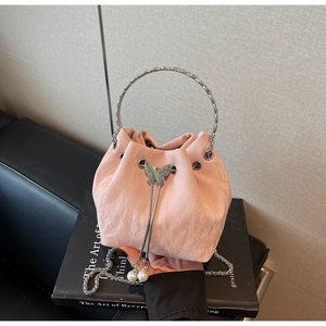 Détail d'un sac seau rose avec papillon argenté et pompon en chaîne de perles
