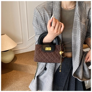 Detail of dark brown quilted crossbody bag with gold twist lock and metallic ball charm