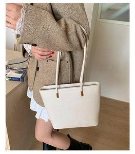 Detail of minimalist cream leather tote bag with elegant golden hardware and long strap