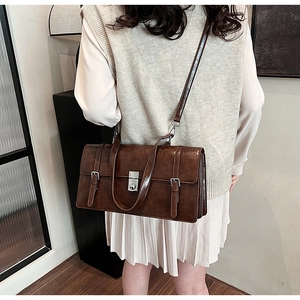 Detail of vintage brown rectangular shoulder bag featuring silver metal buckle and straps