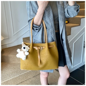 Détail du sac cabas tressé jaune gingembre avec boucle en cuir et pendentif ours
