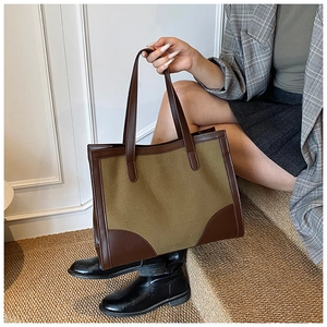 Détail du grand sac cabas en toile vert olive avec anses en cuir marron et base renforcée