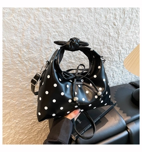 Close-up of black and white polka dot bag with knotted bow handle and metal charms