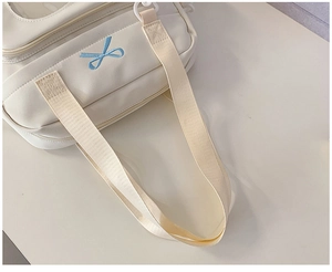 Detail of cream white canvas bag with blue bow embroidery and wide fabric shoulder strap