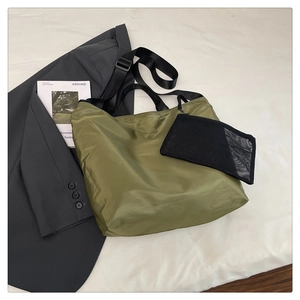 Olive green nylon tote bag with black straps and a small mesh pouch on white fabric