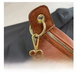 Close-up of golden metal hooks and zipper hardware on vintage brown crossbody bag