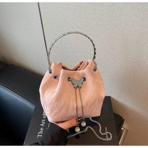 Vue macro d'un sac seau rose en tissu texturé avec cordon et détails de chaîne perle