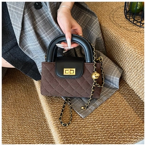 Detail of quilted brown suede handbag with gold turn-lock and adjustable chain strap