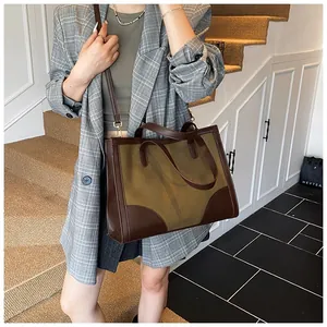 Détail d'un grand sac fourre-tout vert olive avec anses et bandoulière en cuir marron