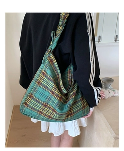 Detail of green plaid canvas shoulder bag with pleated strap and tartan pattern