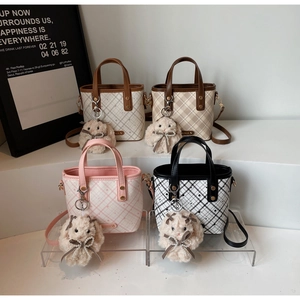 Detailed view of four plaid bucket bags with adjustable straps and plush rabbit charms