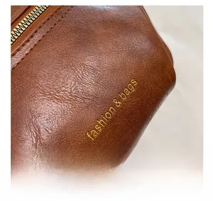 Close-up of brown litchi pattern leather texture and golden metal zipper on cross bag