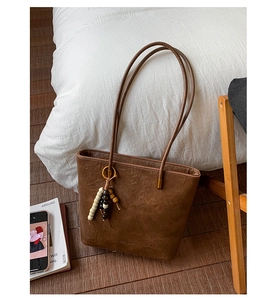 Detailed view of dark brown vintage faux leather tote bag with decorative beaded charms