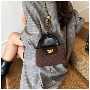 Detail of quilted brown suede bag with black flap and adjustable gold chain strap