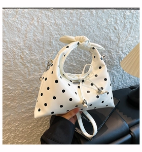 Detail of white polka dot dumpling bag featuring a knotted handle and silver metal beads