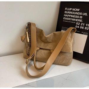 Detail of tan tote bag featuring smooth leather wide strap and baseball glove pendant charm