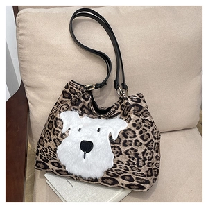 Detail of leopard print tote bag featuring a white plush dog patch and black leather straps