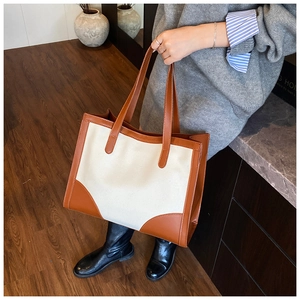 Détail du grand sac cabas en toile avec poignées en cuir marron et coins renforcés