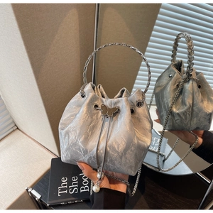 Détail du sac seau argenté avec texture plissée, perles et poignée métallique