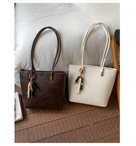 Detail of pleated PU leather texture on large tote bags with decorative wood bead tassels
