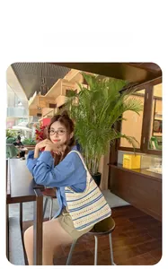 Detailed crochet texture of striped woven shoulder bag shown in an outdoor cafe setting