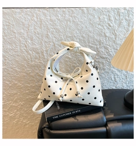 Close-up of white polka dot bag with knotted handle and elegant silver metal details