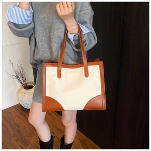 Détail du sac cabas bicolore montrant la toile blanche et les poignées en cuir marron