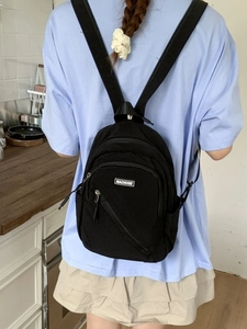 Minimalist black nylon mini backpack with adjustable straps worn in a lifestyle setting