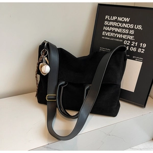 Detail of a black matte PU leather tote bag with unique sports-themed charms and wide strap