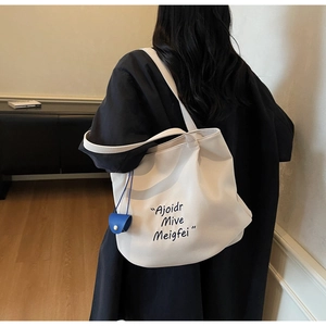 Detail of a large white Korean-style tote bag with black letters and a blue mini pouch
